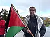 Kvinne har på seg palestinaskjerf og har palestinsk flagg i handa.