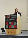 Jelena holder en presentasjon bak ECREA 2024-talerstol på en konferansescene.