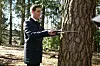 Person i skog som måler diameteren på et tre med et feltinstrument.