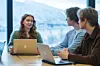 Studenter med bærbare PC-er i møte ved et bord foran store vinduer mot snødekte fjell