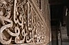 Nærbilde av dekorativt utskåret murverk med buet åpning og mørk passasje.