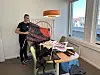 Person står ved et bord med plakater og et banner med politiske budskap i et lyst rom.