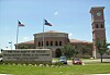 University of Texas at San Antonio-skilt foran campusbygging, flagg og klokketårn.