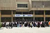 Stor folkemengde foran en universitetsinngang med skilt på arabisk og engelsk.