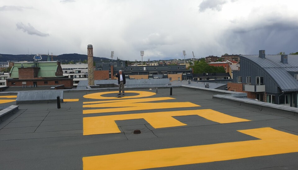 OsloMet-logoen finnes nå også på den femte fasade; taket. Seniorrådgiver Vidar Holum i Avdeling for eiendom har tatt plass i den ene O-en. Foto: OsloMet