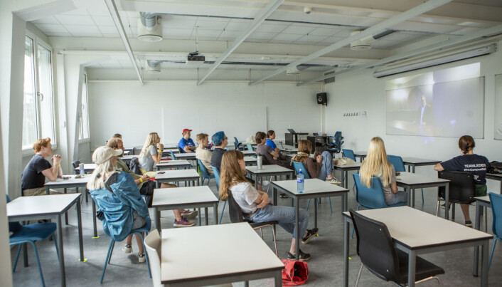 Her fra studiestart i 2020 ved Høyskolen Kristiania. Faddere og studenter følger direktesendt oppstartsseremoni på storskjerm i et klasserom.