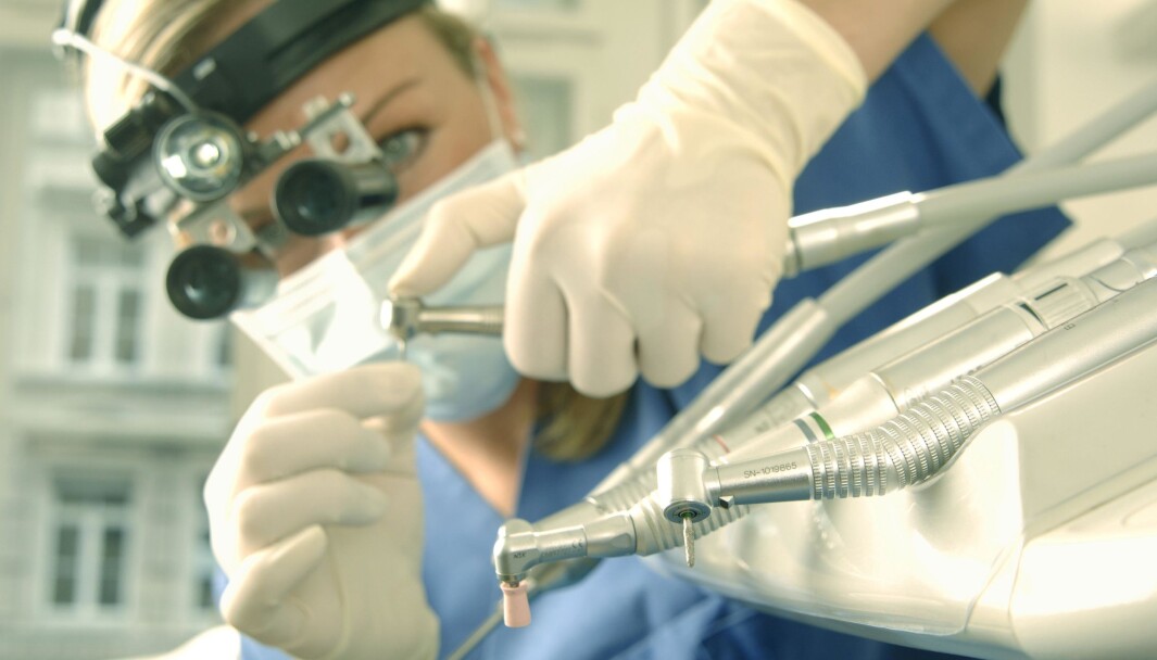 Dentist wearing magnifying loupes preparing a drill Dentist wearing magnifying loupes preparing a drill