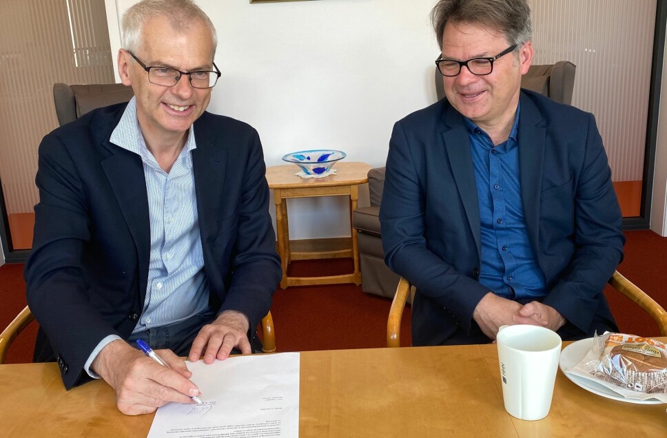 Rektor Øystein Thøgersen (til venstre) signerer på papirene som sier at også NHH nå er med på å finansiere kunnskapsavisen Khrono. Her sammen med styreleder i Khrono, Tore Tungodden .