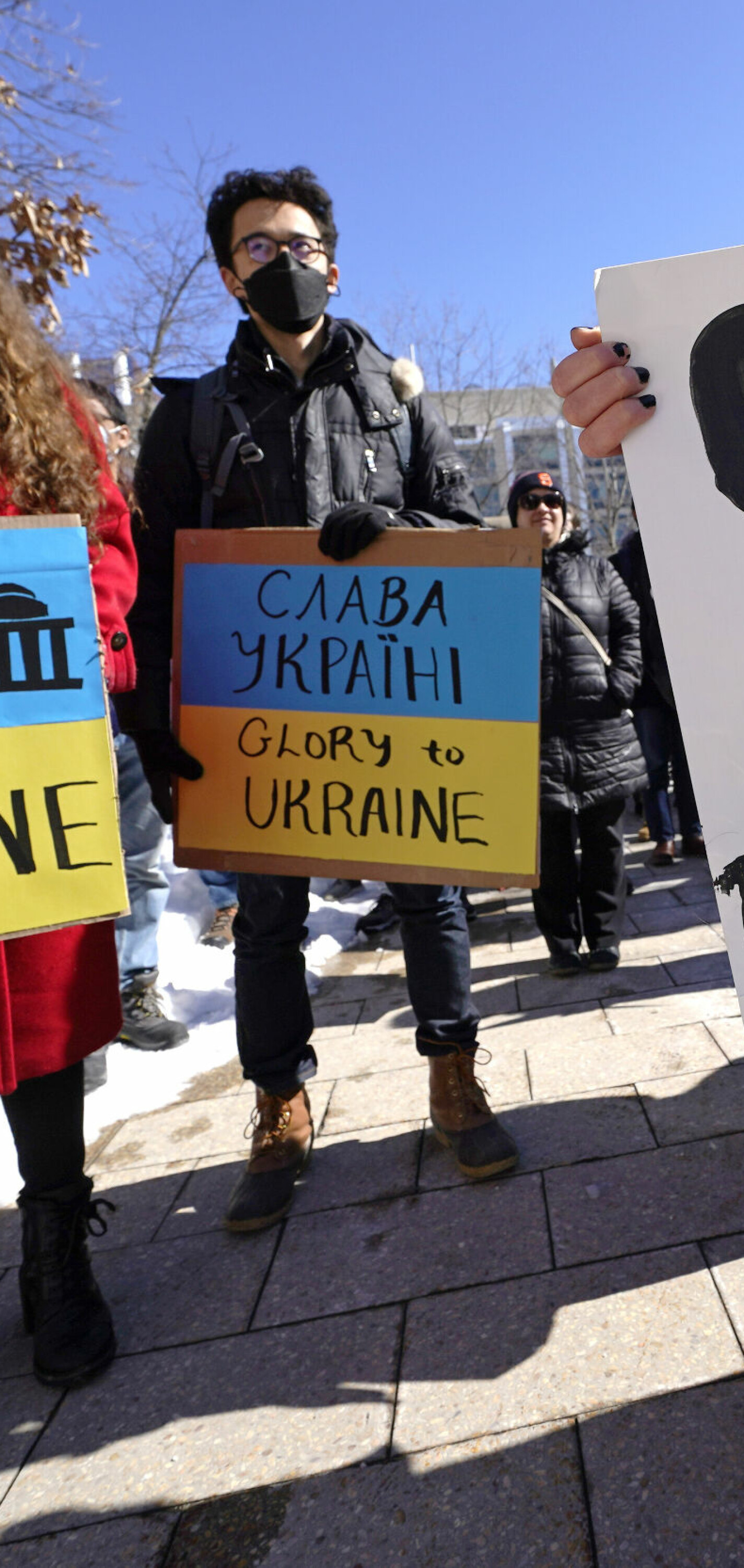 Demonstrators clutch placards during a rally in support of Ukraine, during a protest on Monday, Feb. 28, 2022, at the Massachusetts Institute of Technology in Cambridge, Mass. MIT has severed ties with a research university it helped establish in Russia, citing the country's "unacceptable" invasion of Ukraine. The Cambridge university said it notified the Skolkovo Institute of Science and Technology in Moscow on Friday, Feb. 25, 2022, that it was exercising its right to terminate the MIT Skoltech Program. (AP Photo/Charles Krupa)