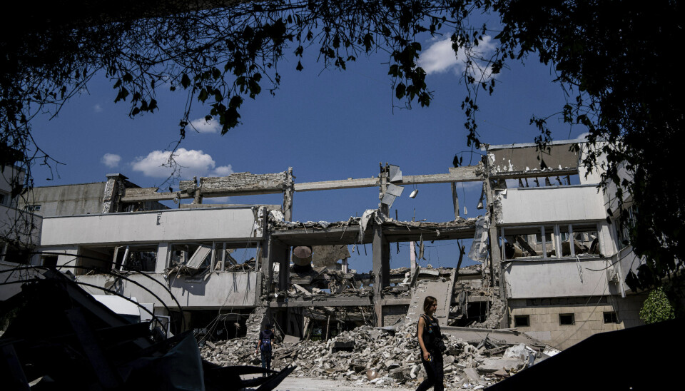 En ukrainsk journalist går i ruinene av Kharkivs universitet for pedagogikk, som er bombet i stykker.