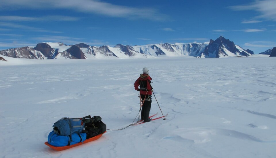 En skiløper med pulk foran et fjellmassiv.