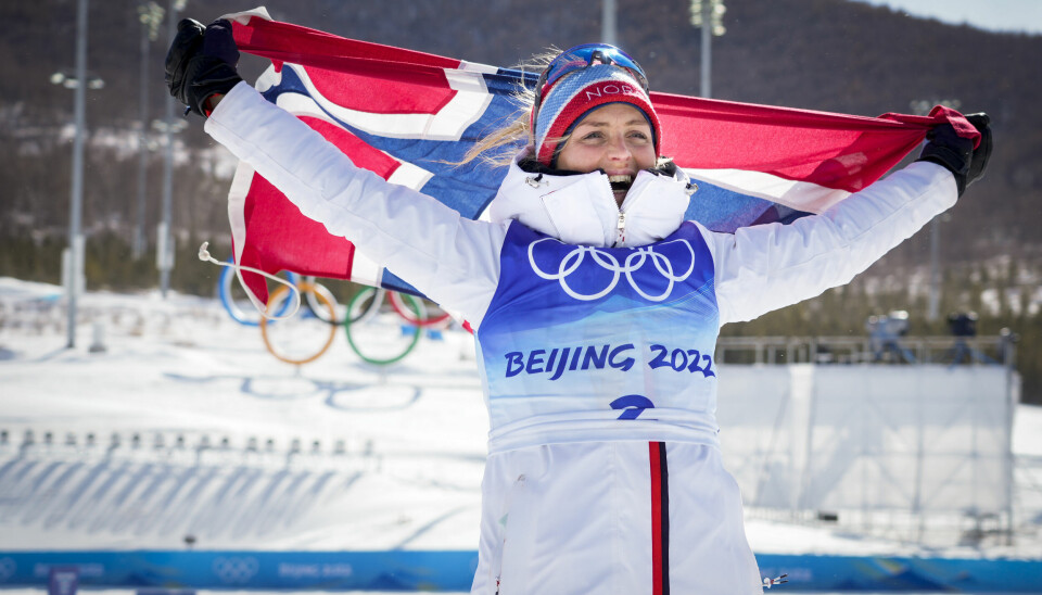 Therese Johaug jubler, iført et norsk flagg under Beijing-OL 2022.