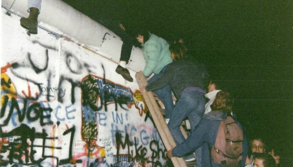 Mennesker klatrer opp på Berlinmuren i november 1989.