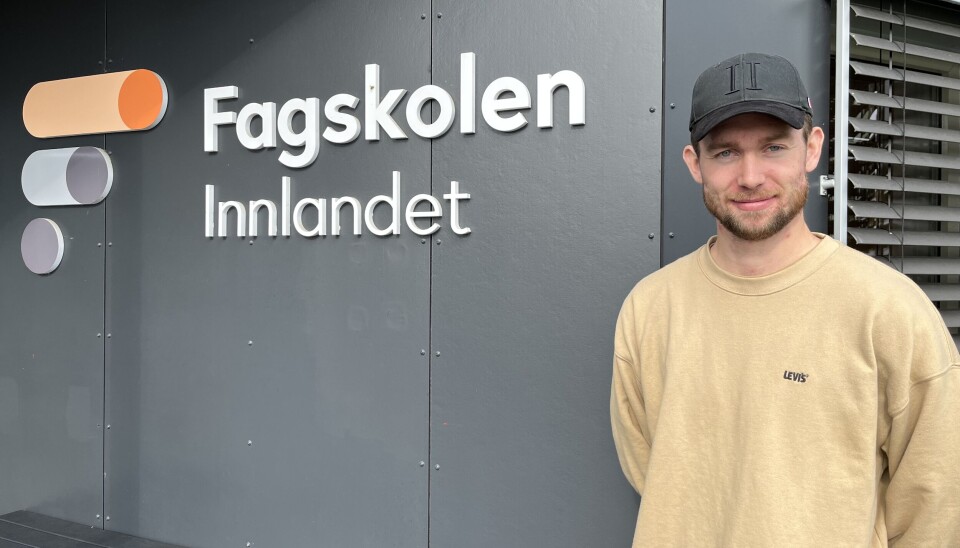 Fagskolestudent står i gul genser og caps utenfor Fagskolen Innlandet.