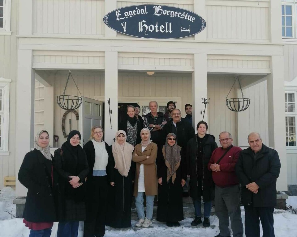 Gruppebilde med 16 personer foran en hvit bygning, det er vinter og snø, Eggedal Hotell mars 2023