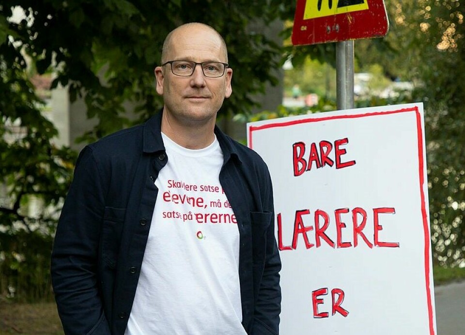 Steffen Handal ved siden av en plakat der det står 'Bare lærere er lærere'.