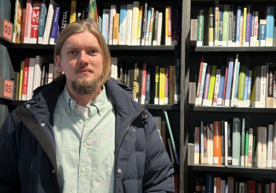 Lerheim syns godt flere studiesteder burde ha grupper for nevrodivergente studenter. Jakob Jensen Høiberg Lerheim er leder for Nevrodivergent Studentforening. Han er en mann med blondt halvtlangt hår og skjegg, og står foran en bokhylle.