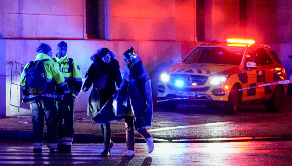 Politibil, politi med blålys og to personer utenfor universitetsbygning