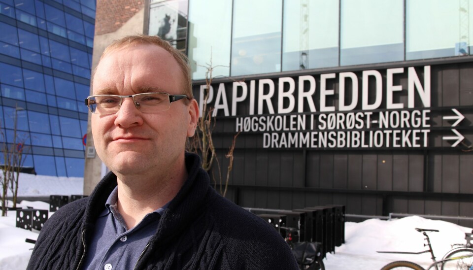 Portrettfoto av Dag Einar Thorsen, en smilende mann med briller og lyst hår. I bakgrunnen står det 'PAPIRBREDDEN' på et bygg med store vinduer. Det er snø på bakken.