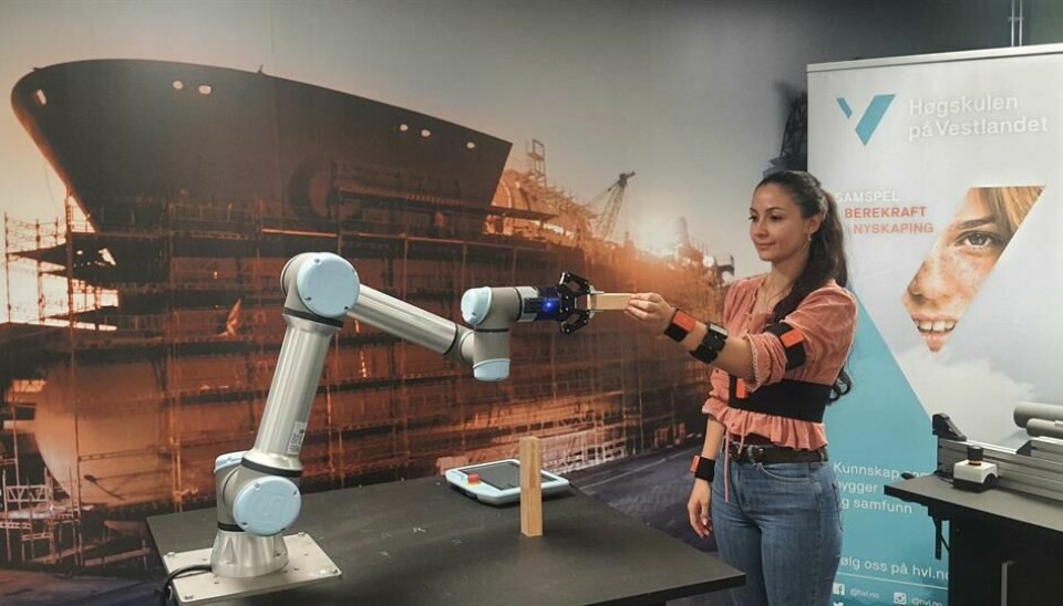 Kvinne demonstrerer hvordan hun samarbeider med en robot.