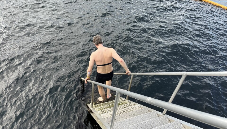 Bildet viser en mann på vei ned en badetrapp til sjøen