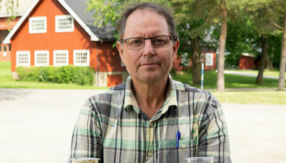 Thomas Cottis på et gårdstun viser fram to glass med gjødsel