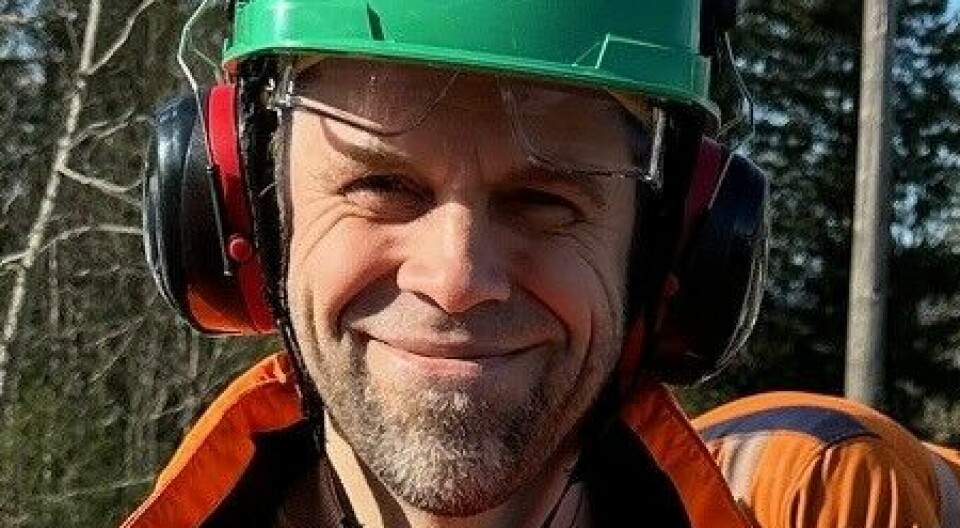 Mann i oransje arbeidsklær og grønn hjelm