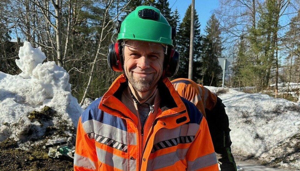 Mann i oransje arbeidsklær og grønn hjelm