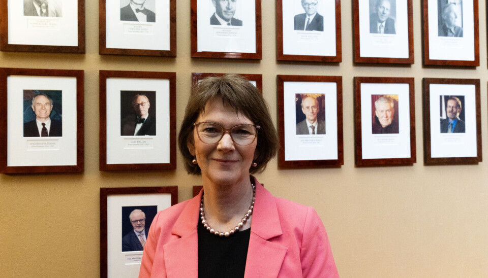 Lise Øvreås, preses i Det Norske Videnskaps-Akademi. I bakgrunnen er bilder av tidligere preseser.