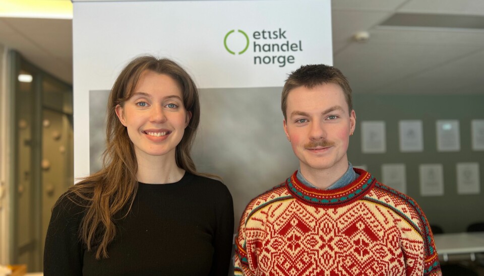 Portrett av Amanda Holli Husum og Simon Burø Ågren foran en plakat hvor det står etisk handel norge.