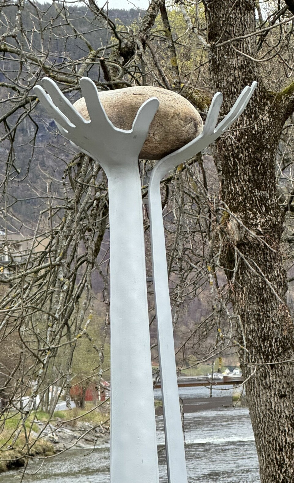 Minnesmerke for Arve Beheim Karlsen, Sogndal, avduka 28. april 2024. To hender som held ein rund elvestein opp mot himmelen.