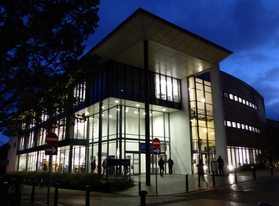 Universitetsbiblioteket på Dundee universitetet i Skottland En moderne bygning med store glassfasader som lyser opp i mørket