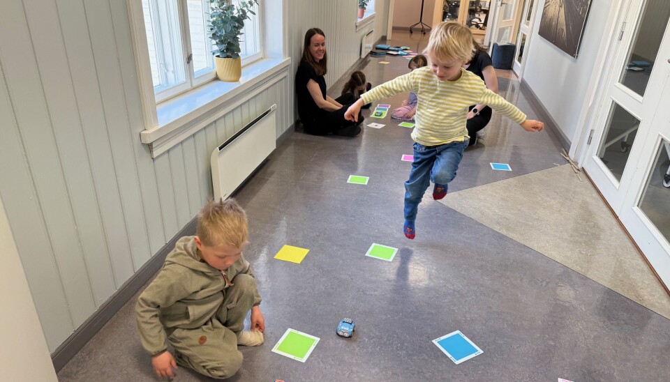 Karl Edvard Persson Benneche jubler over å ha knekt koden. Mattene i ulik farge gjør at de små robotbilene enten stopper, kjører eller svinger. Sigurd Morken Alvheim følger nøye med.