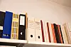 En hylle med noen permer og bøker.