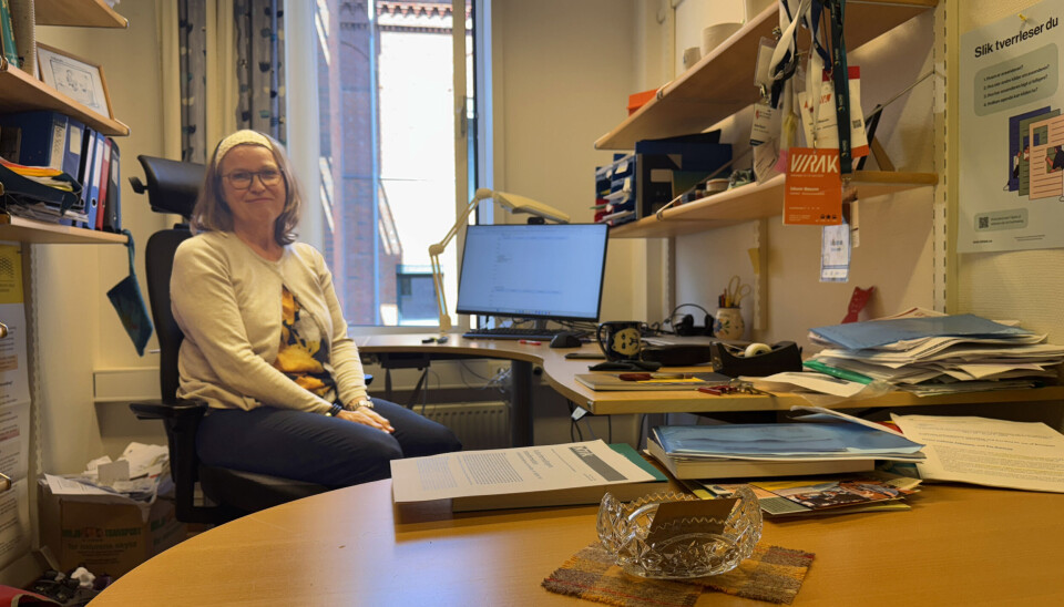 Idunn Bøyum på sitt nyryddede kontor, i anledning sensur av oppgaver. Vanligvis retter hun oppgaver på papir. Av hensyn til studentenes personvern er oppgavene ryddet bort før Khronos besøk. I forgrunnen en skål oppå en rutemønstret stoffbit som er fra Skottland.