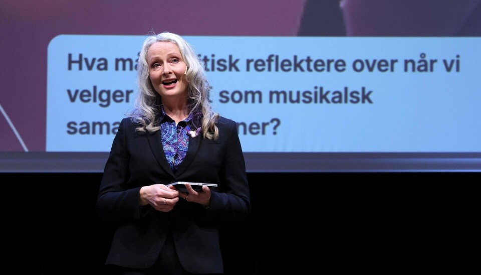 Tine Grieg Viig er førsteamanuensis i musikkpedagogikk ved Høgskulen på Vestlandet, der hun underviser i og forsker på skapende læringsprosesser, post-kritisk pedagogikk og teknologi i utdanning. Kvinne i mørk drakt og lyst hår står foran en lysbildepresentasjon og snakker