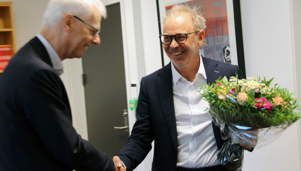 Påtroppende rektor ved NHH, Helge Thorbjørnsen (t.h.), får blomster av avtroppende rektor Øystein Thøgersen. To menn i dress tar hverandre i hånden og overleverer blomster.